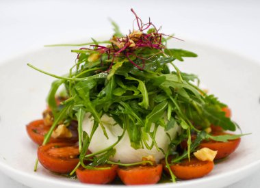 Beyaz tabakta mozzarella, domates ve roka salatası.