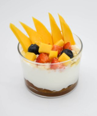 Beyaz arka planda taze mango ve yaban mersinli mango yoğurdu.