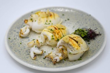 Beyaz arka planda izole edilmiş tabakta ızgara kalamar. Seçici odak.