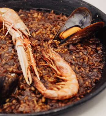 Beyaz arka planda tavada deniz ürünleri paella 'sı.