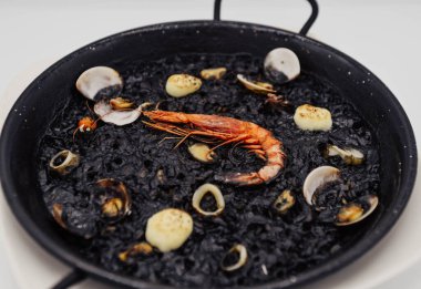 Karides, istiridye ve midyeli siyah pirinç paella.