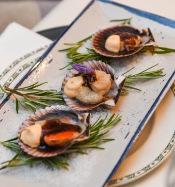 Beyaz tabakta biberiyeli taze çiğ deniz tarakları..