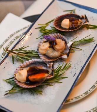 Beyaz tabakta biberiyeli taze çiğ deniz tarakları..