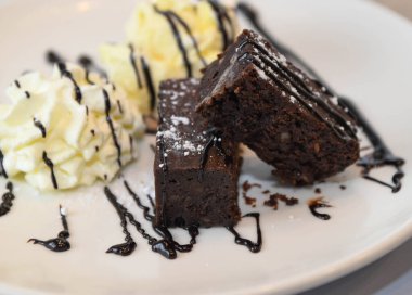 Krem şantili çikolatalı kek ve beyaz tabakta vanilyalı dondurma.