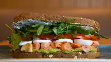 Somon, roka, domates ve mozzarella ile mısır ekmekli sandviç.