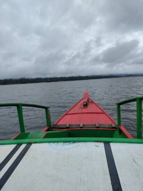Doğanın dingin güzelliğini bu büyüleyici fotoğrafta tecrübe edin. Uzakta, sakin bir alp gölünün kristal berrak sularında mükemmel bir şekilde yansıtılan görkemli bir dağ sırası beliriyor. Bu tekne başı..
