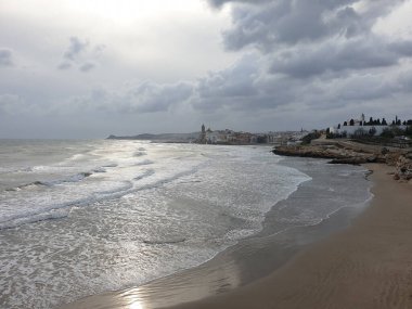 Sörfçülerin olduğu güzel Sitges kasabası, yağmurdan önce Sitges 'deki sahil manzarası, dramatik deniz.