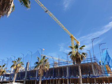 Mavi gökyüzü, palmiye ağaçları, İspanya 'da inşaat halindeki vinç ve bina