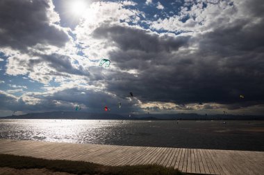 Denizde yağmurdan önce dramatik bulutları olan bir sürü uçurtma avcısı, Delta del Ebro 'daki Trabucador sahilinde uçurtmacılar.