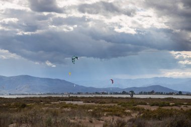 Denizde yağmurdan önce dramatik bulutları olan bir sürü uçurtma avcısı, Delta del Ebro 'daki Trabucador sahilinde uçurtmacılar.