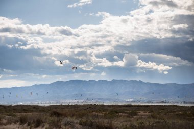 Denizde yağmurdan önce dramatik bulutları olan bir sürü uçurtma avcısı, Delta del Ebro 'daki Trabucador sahilinde uçurtmacılar.