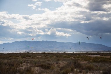 Denizde yağmurdan önce dramatik bulutları olan bir sürü uçurtma avcısı, Delta del Ebro 'daki Trabucador sahilinde uçurtmacılar.
