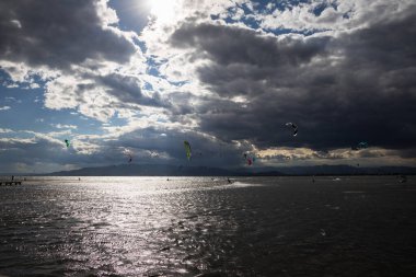 Denizde yağmurdan önce dramatik bulutları olan bir sürü uçurtma avcısı, Delta del Ebro 'daki Trabucador sahilinde uçurtmacılar.