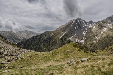 Dağın zirvesinde yaz aylarında kar ve yeşil çimlerle kaplı, Andorra dağlarında bulutlu, Arinsal