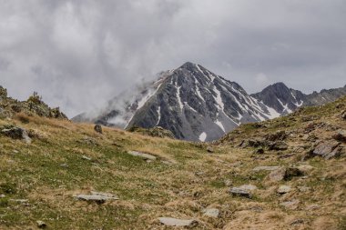 Dağın zirvesinde yaz aylarında kar ve yeşil çimlerle kaplı, Andorra dağlarında bulutlu, Arinsal