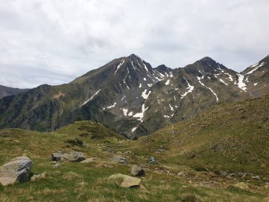 Dağın zirvesinde yaz aylarında kar ve yeşil çimlerle kaplı, Andorra dağlarında bulutlu, Arinsal