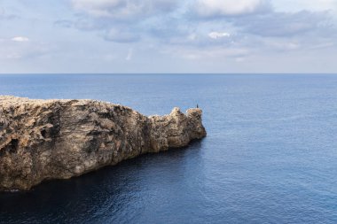 Ciutadella, Menorca 'da Pont d' en Gil, denizdeki kayadan köprü, burunda kemer, kayanın ucunda yalnız insan