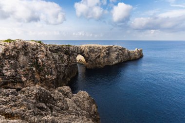Ciutadella, Menorca 'da Pont d' en Gil, denizdeki kayadan köprü, burunda kemer, kayanın ucunda yalnız insan