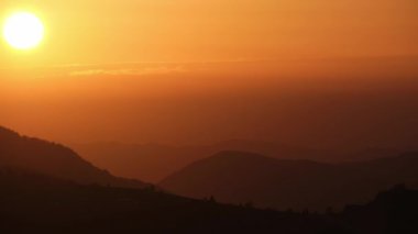 Büyük güneş bulutların ardında batıyor, tepe manzarasında alacakaranlıkta. Yüksek kalite 4k görüntü