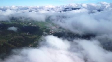 Sis, ladin ormanlarının üzerine eser. Sisli bir günde dağ tepelerindeki ladin ormanlarının hava görüntüleri. Sabahları alçak ve merkezi bulutlar. İHA görüntüsü, kuş bakışı görüntüler, gerçek zamanlı görüntüler. 