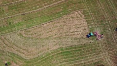 Çiftçi bir traktör Ted 'in yardımıyla hasat edilen samanları taşıyarak samanların kurutulmasını hızlandırır. Top wiev. Yüksek kalite 4k görüntü
