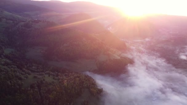 カルパチア山脈の山の風景の農村部の谷の霧と反転雲の空中ドローンビューでは 日の出 丘の後ろから明るい太陽が昇る Fhdドローンビデオ — ストック動画