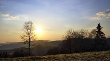 Orman tepe ufkunun ardında gün batımı. Bulutlar pastel renklerle renklidir. Yüksek kalite 4k görüntü