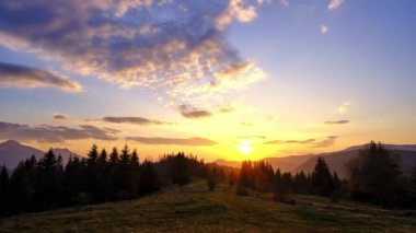 Orman dağ manzarasında gün batımı. Bulutlar pastel renklerle renklidir. Zaman ayarlı, yüksek kalite 4K görüntü