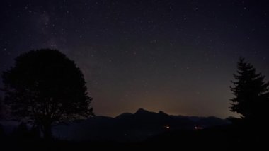 Samanyolu Yıldızları ve Bulutları ile Gece Gökyüzü, ağaçlarla dolu tepe tepe manzarası, geceden güne. Yüksek kalite 4k görüntü