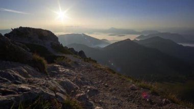 Dağlık bir çevrede gün doğumunun hızlandırılmış görüntüleri, kayalık dağ tepesi, ters bulutlarla kaplı vadideki manzara. Yüksek kalite 4k görüntü