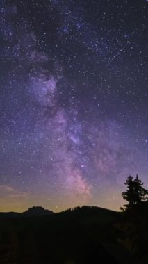 Samanyolu evreni, karanlık akşam bulutlarında yıldız izleri. Perseid Meteor yağmuru, ormandaki dağ manzarası, ateşin yanındaki insanlar. Yüksek kalite 4k görüntü