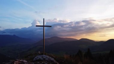 Dağlık kırsaldaki bir tepenin üzerindeki dini bir Hıristiyan çelik haçının havadan görünüşü. Yüksek kalite 4k görüntü