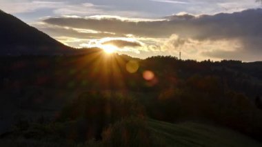 Sonbahar manzarasında, ormanlık tepelerin arkasındaki batan güneş. Yüksek kalite 4k görüntü