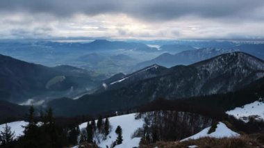 Kışın dağlık tepe manzarası, bulutlu rüzgarlı hava, hızlı bulut hareketleri, zaman ayarlı. Yüksek kalite 4k görüntü