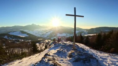 Kış doğasının manzarası, gündoğumunda karlı tepede çelik haçla kaplı, dindar Hıristiyan arka planı. Yüksek kaliteli FullHD görüntüler