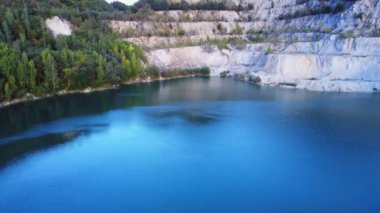 Ağaçlar ve kayalarla çevrili büyük bir gölü olan çarpıcı bir doğal manzara.,