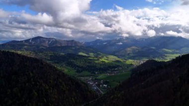 Dağların ve ormanların altındaki bir vadide bir dağ köyü. Baharın ilk yeşil ağaçları, kabarık bulutlar, güzel bahar manzarası. Yüksek kalite 4k görüntü