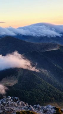 Alacakaranlık güneşinin güzel ışığı vahşi, sisli doğada Alp dağlarında alçak bulut dalgaları. Otdoor sosyal medya hikayesi için zaman kaybı, Yavaş pan.