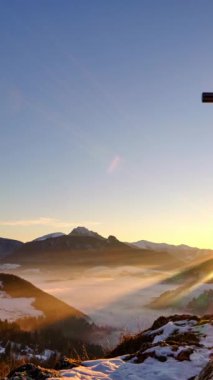 Hristiyan haçı üzerinde gün batımı huzurlu karlı ve sisli kış manzarası vadide sisli. Yüksek kalite 4k görüntü