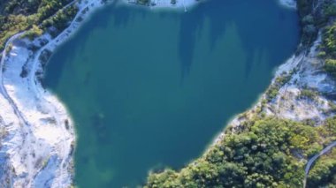  Bir yol, evler ve ağaçlarla çevrili eski bir taş ocağındaki turkuaz bir gölün üstünden hava manzarası. Yüksek kalite 4k görüntü