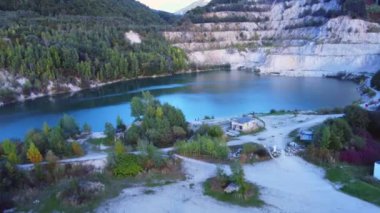  Bir yol, evler ve ağaçlarla çevrili eski bir taş ocağındaki turkuaz bir gölün üstünden hava manzarası. Yüksek kalite 4k görüntü