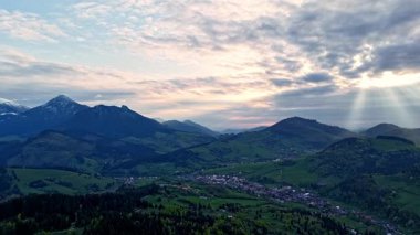  Güneş ışınlarının bulutları delip geçtiği, sakin tepeler ve vadiler üzerinde dramatik ve güzel bir atmosfer yaratan Karpatya kırsal dağ manzarasının havadan görünüşü..