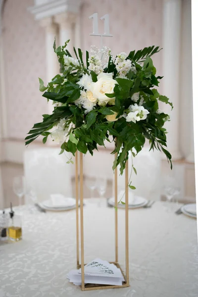 Wedding centerpieces, with metal vase and green fresh flowers arrangements. Wedding day. Wedding decor.