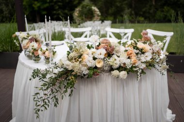 Güzel çiçeklerle dolu bir düğün resepsiyonunda ana masa. Düğün günü. Beyaz ve şeftali çiçekli düğün desenleri.