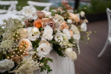 Güzel çiçeklerle dolu bir düğün resepsiyonunda ana masa. Düğün günü. Beyaz ve şeftali çiçekli düğün desenleri.