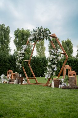 Düğün töreni. Çok güzel ve şık altıgen düğün kemeri, çeşitli taze çiçeklerle süslenmiş, bahçede duruyor. Düğün günü. Taze çiçek süslemeleri.
