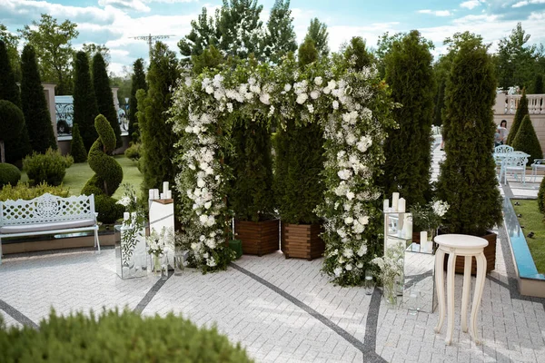Wedding. Wedding ceremony. Arch. Arch, decorated with white flowers standing in the woods, in the wedding ceremony area. Wedding day.