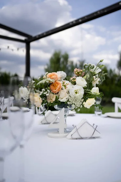 Table centerpiece with white and peach rustic floral arrangement in glass vase. Rustic wedding table. Rustic wedding table. Fresh flowers arrangements for wedding day.