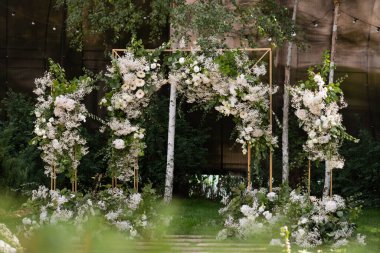 Wedding ceremony. Very beautiful and stylish wedding arch, decorated with various fresh flowers, standing in the garden. Wedding day. Fresh flowers decorations. Wedding day.