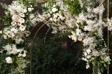 Wedding ceremony. Very beautiful and stylish wedding arch, decorated with various fresh flowers, standing in the garden. Wedding day. Fresh flowers decorations. Wedding day.